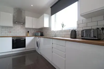 a white kitchen with white cabinets and a window at Signature - Hattrix View in Cumbernauld