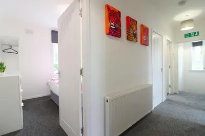 a hallway with white walls and paintings on the wall at Signature - Hattrix View in Cumbernauld