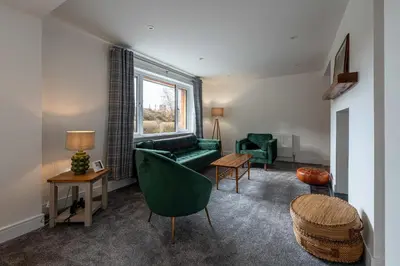 a living room with a green couch and a window at Strathfillan Lodge in Crianlarich