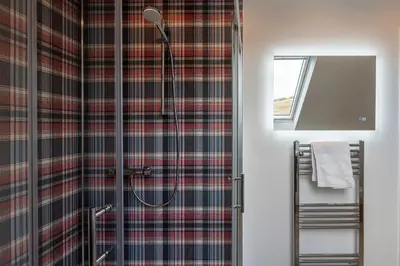 a bathroom with a shower with a plaid shower curtain at Strathfillan Lodge in Crianlarich