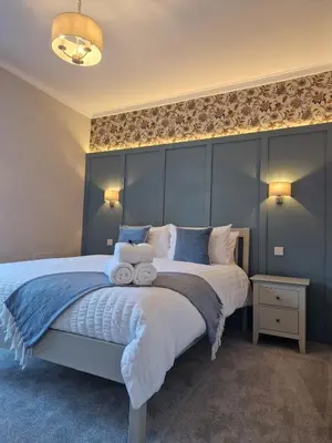 a bedroom with a large bed with blue walls at City Residence Free Parking in Stirling
