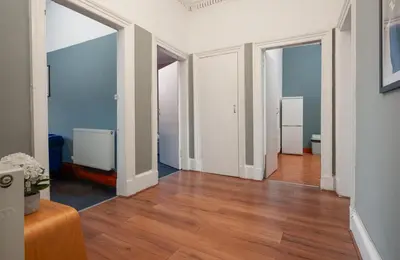 an empty living room with wood floors and doors at Family and Group Stay 2BR by Park Sleeps 7 in Glasgow