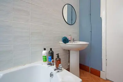 a bathroom with a sink and a bath tub and a mirror at Family and Group Stay 2BR by Park Sleeps 7 in Glasgow
