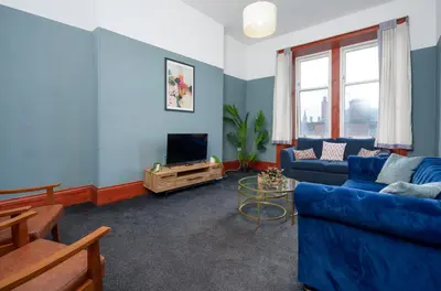 a living room with a blue couch and a tv at Family and Group Stay 2BR by Park Sleeps 7 in Glasgow