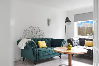 a living room with a green couch and a table at 3BR Family House with Free Parking in West Lothian in Whitburn