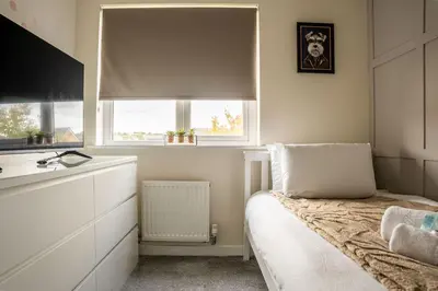 a small bedroom with a bed and two windows at JustStay Glasgow - 3 Bedroom Luxury Villa with free parking in Bailleston