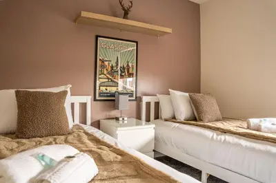a bedroom with two beds and a picture on the wall at JustStay Glasgow - 3 Bedroom Luxury Villa with free parking in Bailleston