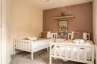 two white beds in a bedroom with a wall at JustStay Glasgow - 3 Bedroom Luxury Villa with free parking in Bailleston