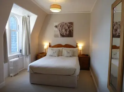 a bedroom with a bed with two lamps and a window at Camus House, Lochside Guest House in Onich