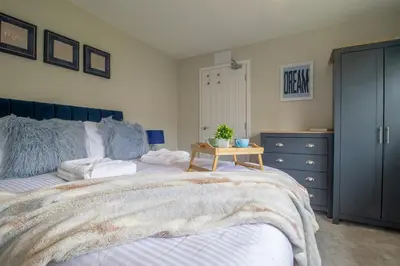a bedroom with a bed and a dresser and a table at Gray House-Modern 2BR close to Loch Lomond in Alexandria