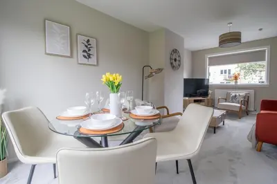 a dining room with a glass table and white chairs at Gray House-Modern 2BR close to Loch Lomond in Alexandria