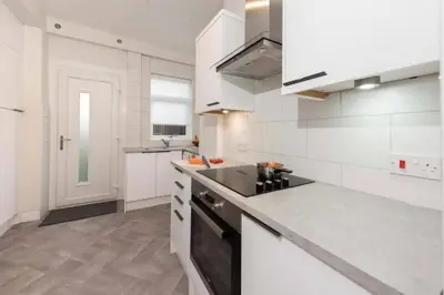 a kitchen with white cabinets and a black stove at Dalziel House-3 bedroom Hamilton in Hamilton