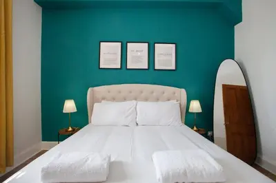a bedroom with a white bed with a green wall at 1 Bed Cosy Loch Lomond base in Bonhill