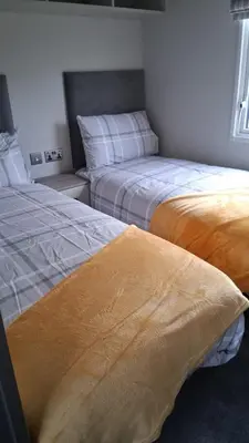 two beds sitting next to each other in a room at Three Lochs Holiday Park- Lochwood Caravan in Newton Stewart