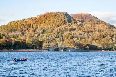 a boat in the middle of a lake with a bridge at Lochfyne-View Apartment in Inveraray