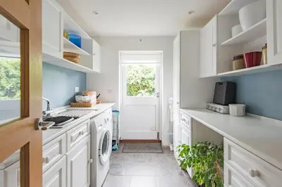 a kitchen with white cabinets and a washing machine at St Mary's House by Keepers Cottages in Moffat