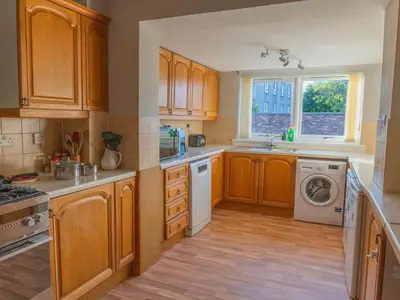 a kitchen with wooden cabinets and a washer and dryer at 3 Bedroom Home, Peaceful Garden in Edinburgh