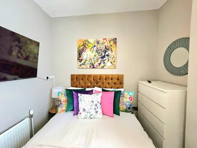 a small bedroom with a bed with colorful pillows at Sensational Stay- Fountainbridge in Edinburgh