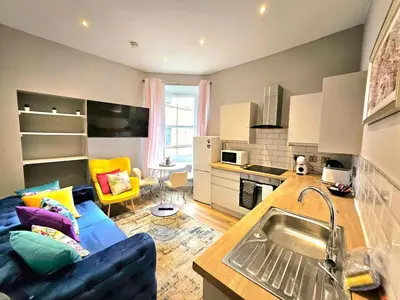 a kitchen and living room with a blue couch in a room at Sensational Stay- Fountainbridge in Edinburgh