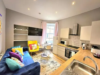 a living room with a blue couch and a kitchen at Sensational Stay- Fountainbridge in Edinburgh