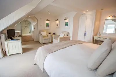 a bedroom with a white bed and a living room at The Bay Rooms at Glenisle Hotel in Lamlash