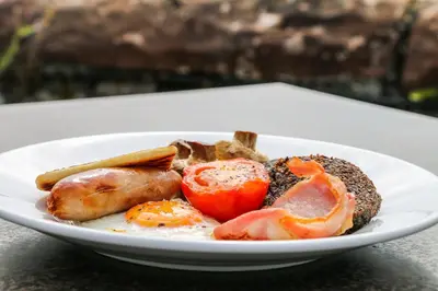 a plate of food with eggs sausage and tomatoes at The Bay Rooms at Glenisle Hotel in Lamlash
