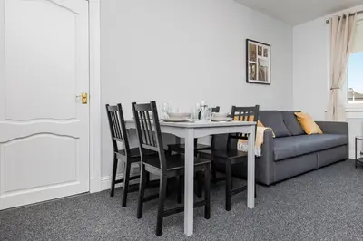 a dining room with a table and chairs and a couch at Ideal Work Stays 3BR Free Parking Sleeps 6 in Falkirk