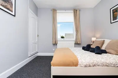 a white bedroom with a bed and a window at Ideal Work Stays 3BR Free Parking Sleeps 6 in Falkirk