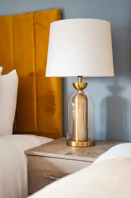 a lamp on a night stand next to a bed at Coat Apartment in Coatbridge