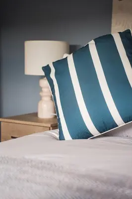 a bed with a blue and white pillow and a lamp at Coat Apartment in Coatbridge
