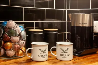 three coffee mugs sitting on a counter next to a coffee maker at Stylish 2Bedroom Flat - Central Oban in Oban