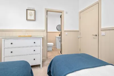 a bedroom with a bed and a dresser and a bathroom at Luxury 3BD Central Apt with Tower & Seaviews in Oban