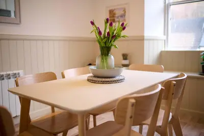 a dining room table with a vase of flowers on it at Luxury 3BD Central Apt with Tower & Seaviews in Oban