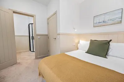 a bedroom with a white bed with a green pillow at Luxury 3BD Central Apt with Tower & Seaviews in Oban