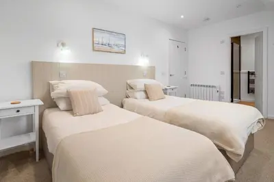 two beds in a room with white walls at Breathtaking Sea Views - Luxury 2 BD Apt in Oban