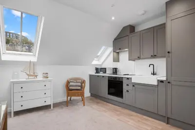 a kitchen with gray cabinets and a sink and a window at Breathtaking Sea Views - Luxury 2 BD Apt in Oban