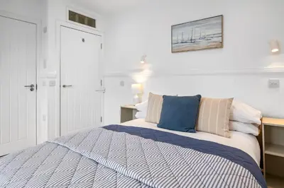 a white bedroom with a bed with blue pillows at Breathtaking Sea Views - Luxury 2 BD Apt in Oban