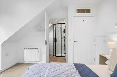 a white bedroom with a bed and a mirror at Breathtaking Sea Views - Luxury 2 BD Apt in Oban