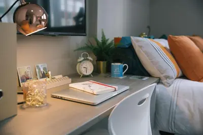 a desk with a keyboard and a clock on a bed at For Students Only - George Street in Glasgow in Glasgow