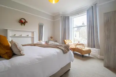 a bedroom with a bed and a window and a chair at Cairnhill House - cosy 3 bedroom in Airdrie