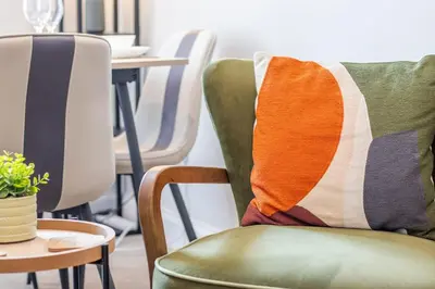 a green chair with a colorful throw pillow on it at Cairnhill House - cosy 3 bedroom in Airdrie