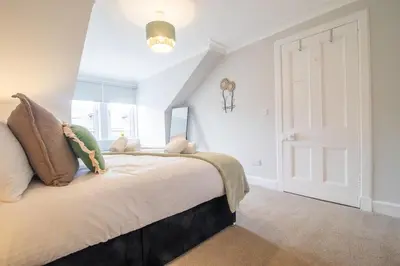 a bedroom with a large bed and a window at Cairnhill House - cosy 3 bedroom in Airdrie