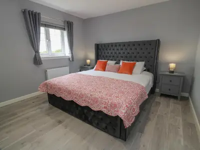 a bedroom with a large bed with red pillows at The Dairy in Airdrie