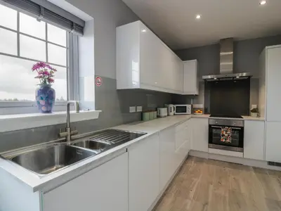 a kitchen with white cabinets and a sink at The Dairy in Airdrie