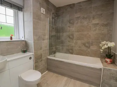 a bathroom with a tub and a toilet and a sink at The Dairy in Airdrie