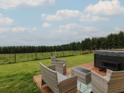 a deck with chairs and a fireplace and a field at The Dairy in Airdrie