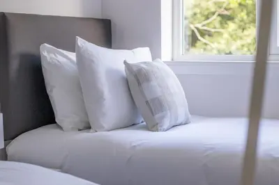 a bed with white pillows and a window at Modern 2-Bedroom Home near Glasgow & Edinburgh in Airdrie