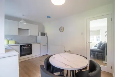 a kitchen with a table and chairs in a room at Modern 2-Bedroom Home near Glasgow & Edinburgh in Airdrie