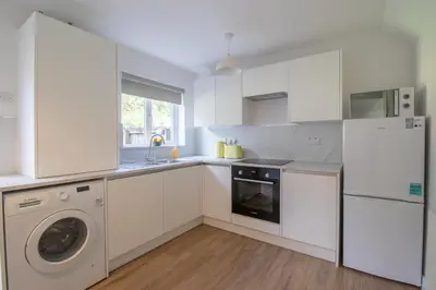 a kitchen with white cabinets and a washer and dryer at Modern 2-Bedroom Home near Glasgow & Edinburgh in Airdrie