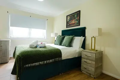 a bedroom with a large bed with a green bedspread at 2 BDR Apt At Caledonia Luxe Stays Short Lets & Serviced Accommodation Airdrie in Airdrie